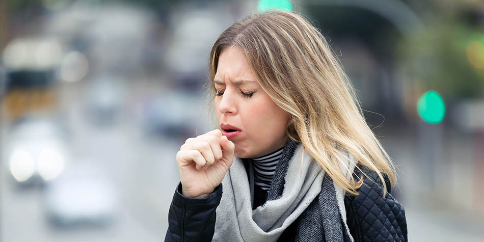 Woman coughing outdoors
